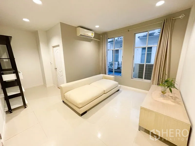 Townhouse for rent in Yan Nawa, Bangkok - Cozy multipurpose room with cream sofa, air conditioning, large windows and neutral decor.