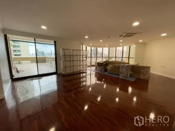 公寓 出租在Khlong Toei, Bangkok - 宽敞客厅，亮泽木地板，筒灯，落地推拉门通往大阳台，城市景观