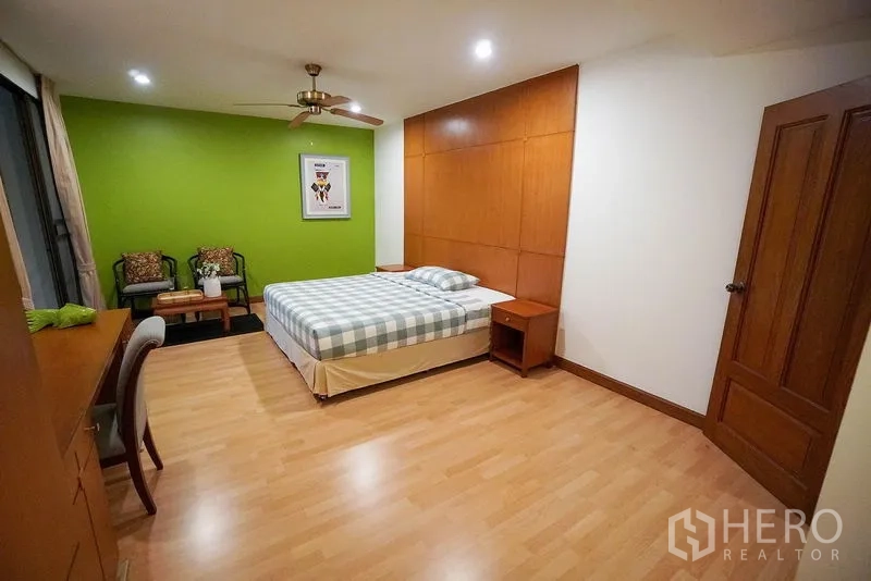 Apartment for rent in Watthana, Bangkok - Third bedroom with green accent wall, study desk and ceiling fan.