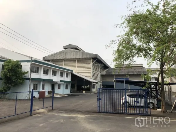 Factory for rent in Lam Luk Ka, Pathum Thani - Gated entrance to a standalone factory with a two‑storey office and large warehouse behind.