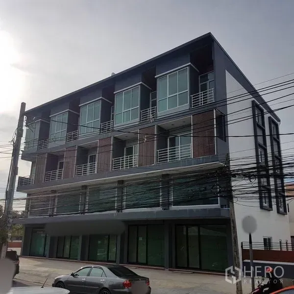 Home Office for sale in Lat Phrao, Bangkok - Modern four-storey home office facade with large glass windows and ground-floor shopfronts in Lat Phrao.
