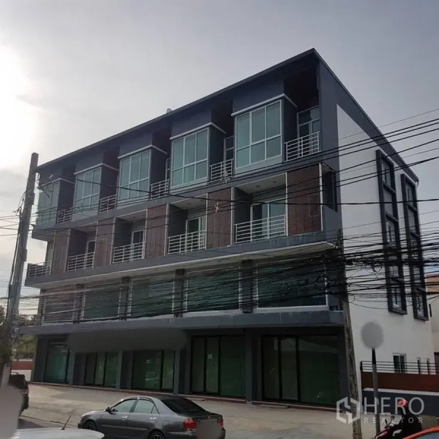 Home Office for sale in Lat Phrao, Bangkok - Modern four-storey home office facade with large glass windows and ground-floor shopfronts in Lat Phrao.