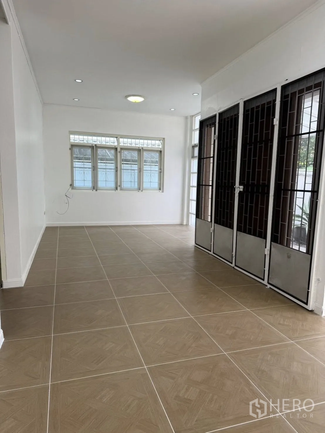 独栋房屋 for rent in Khlong Toei, Bangkok - 宽敞客厅，瓷砖地面，大窗户与金属护栏门。
