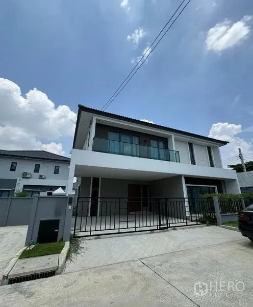Detached House for rent in Don Mueang, Bangkok - Street view of gated modern two-storey house with covered parking.