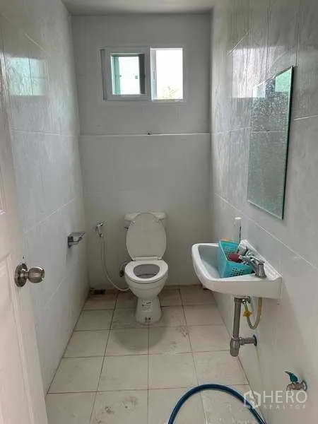 货栈 出租在Pak Kret, Nonthaburi - 仓库内的卫生间，带坐便器、洗手盆和小窗。