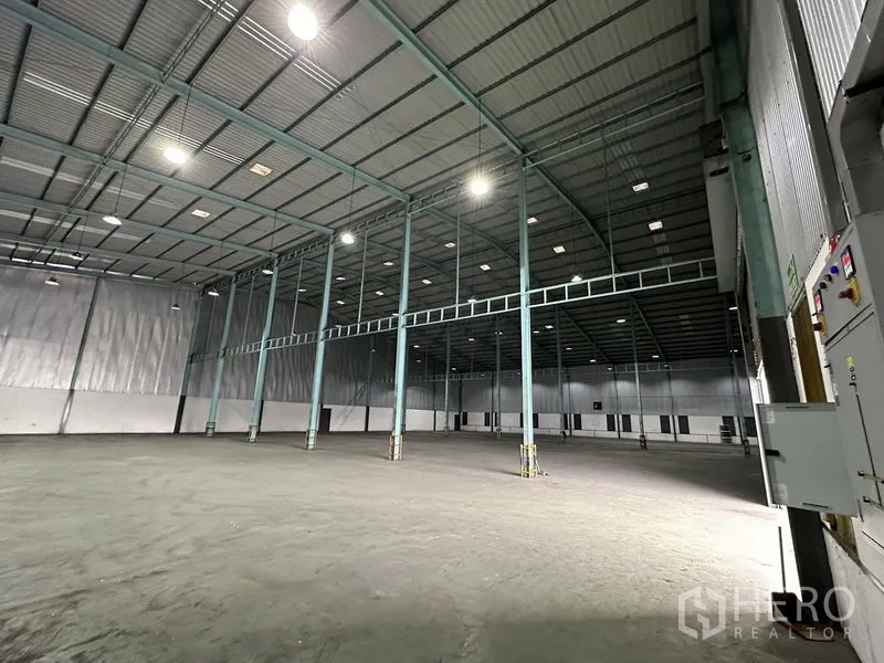 Warehouse for rent in Mueang Samut Prakan, Samut Prakan - Spacious warehouse interior with high steel columns, bright high-bay lights and smooth concrete floor.