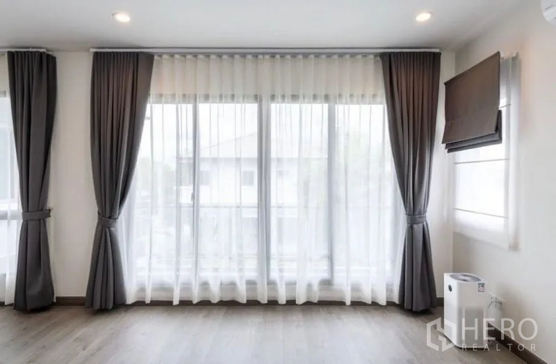 Detached House for rent or sale in Saphan Sung, Bangkok - Bright room with wide windows, sheer drapes, and dark gray curtains.