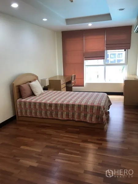 公寓 出租在Watthana, Bangkok - 明亮次卧，单人床、书桌、木地板与窗帘。