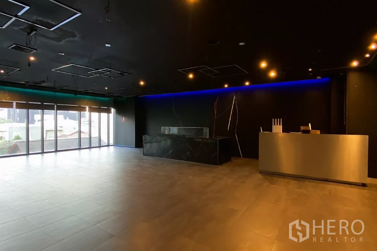 Retail Space for rent - Open retail floor with panoramic glazing and reception counters along a feature-lit wall.
