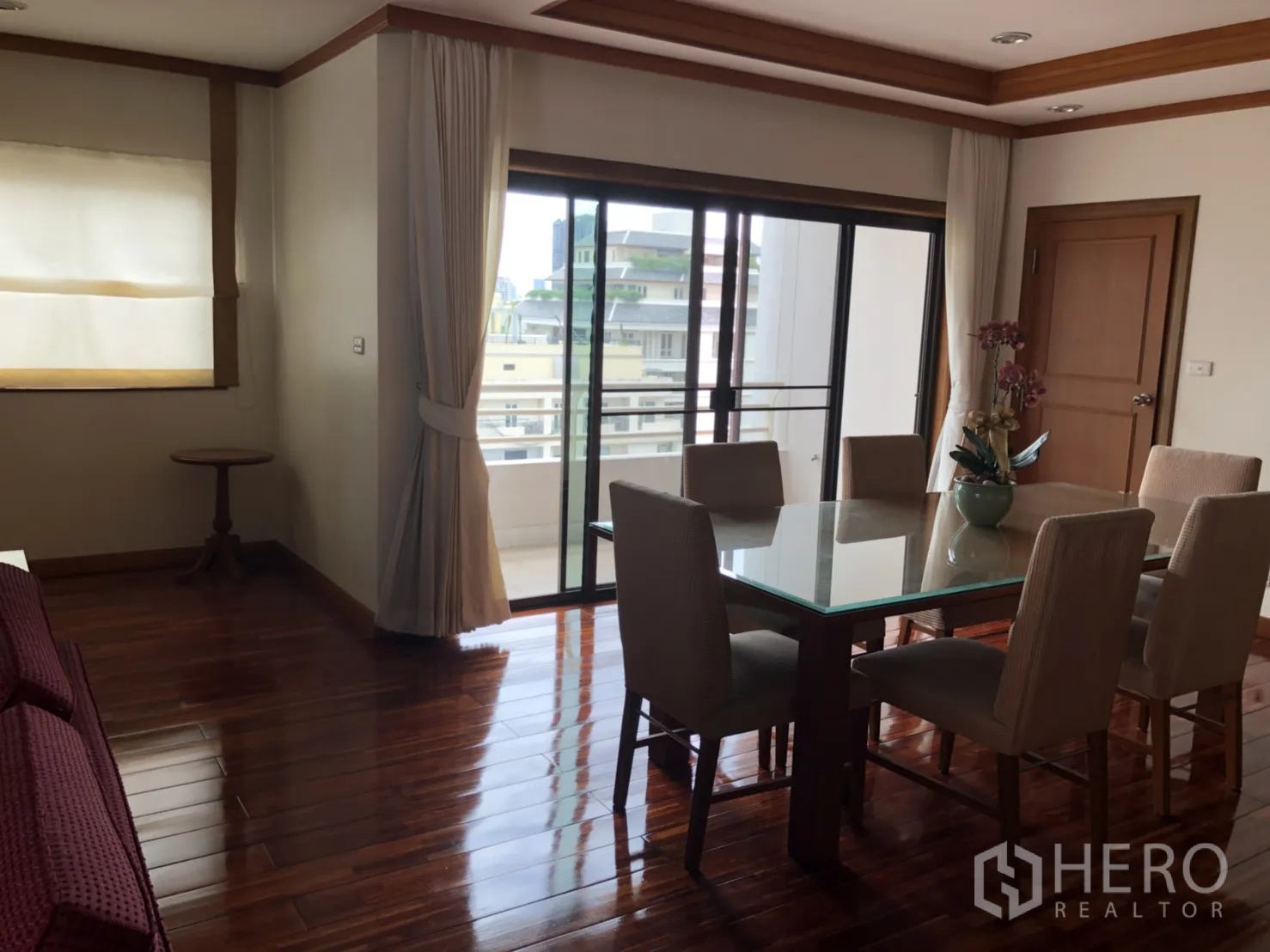 Apartment for rent in Bang Rak, Bangkok - Bright dining area with glass-top table, six chairs, hardwood floors and sliding doors to a balcony.