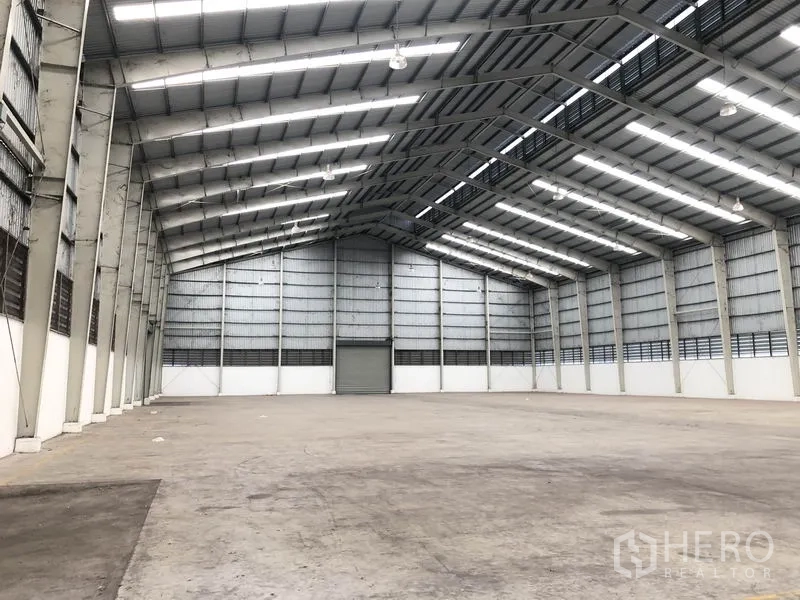 Factory for rent in Wang Noi, Phra Nakhon Si Ayutthaya - Spacious warehouse interior featuring a high steel truss roof with skylights and a smooth concrete floor.