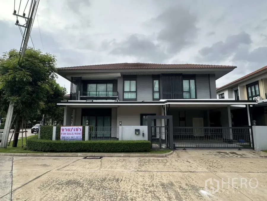 Detached House for rent or sale in Lam Luk Ka, Pathum Thani - Modern two-storey detached house with gated carport and For Sale/Rent sign on a corner plot.