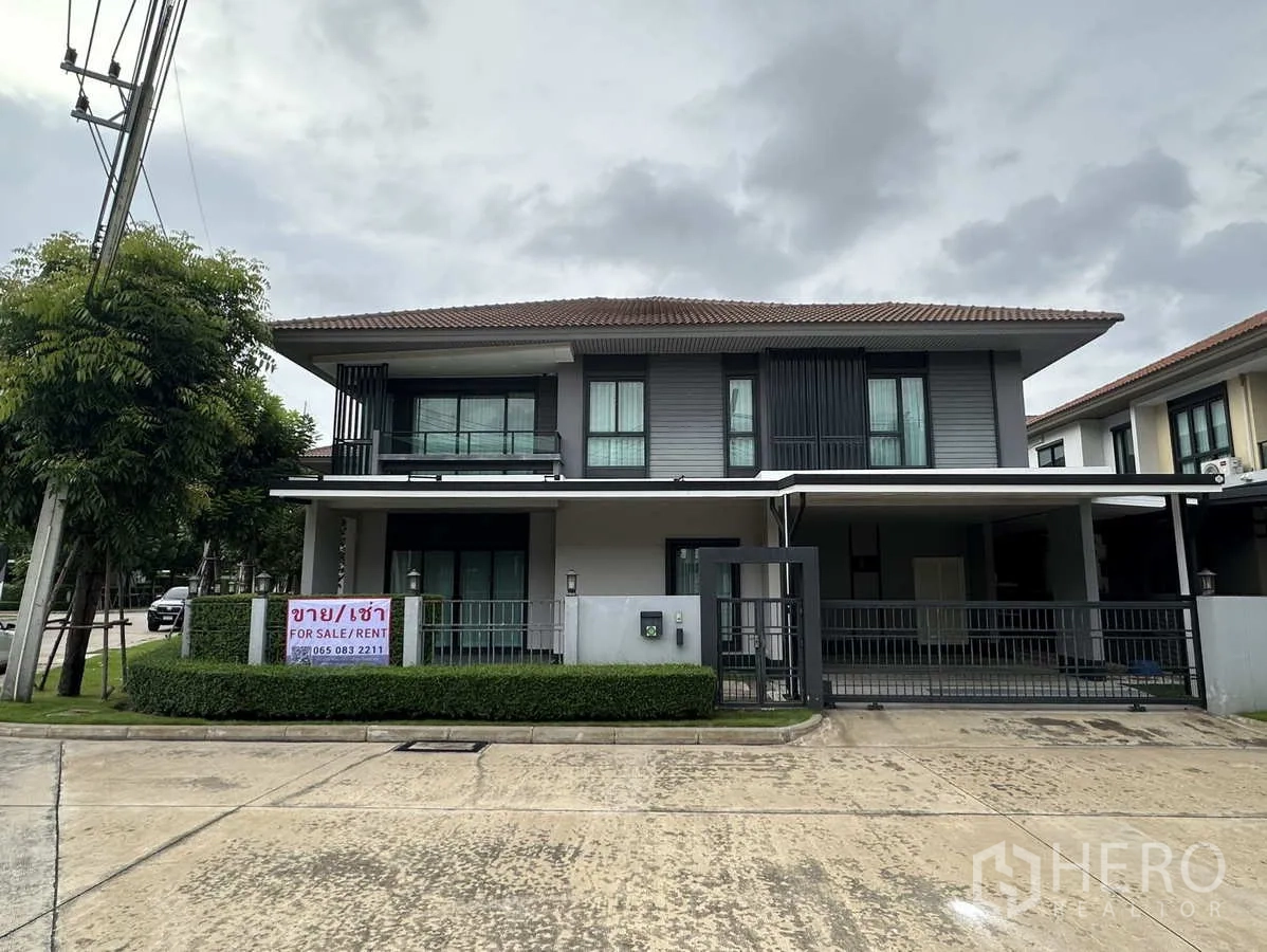 Detached House for rent or sale in Lam Luk Ka, Pathum Thani - Modern two-storey detached house with gated carport and For Sale/Rent sign on a corner plot.