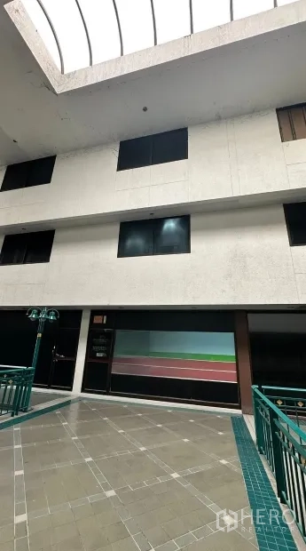 办公室 for rent in Huai Khwang, Bangkok - 室内中庭带天窗与瓷砖地面，绿色栏杆环绕单元入口。