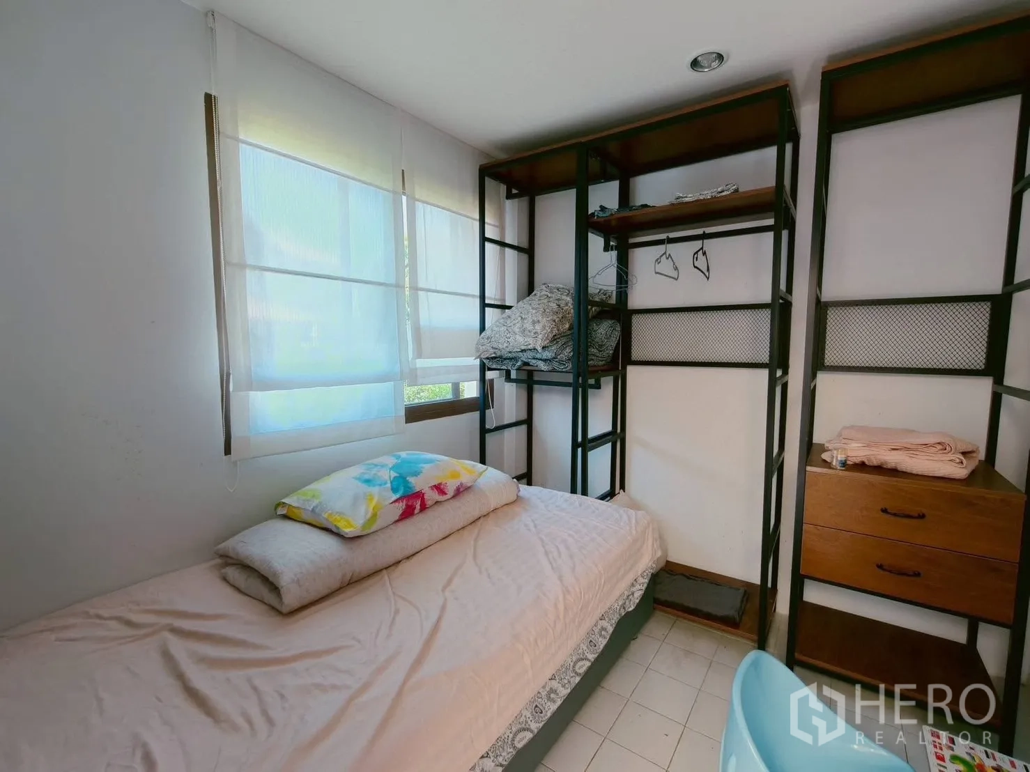 Detached House for rent in Lat Krabang, Bangkok - Compact bedroom with single bed, open metal shelving wardrobes and sheer blinds.