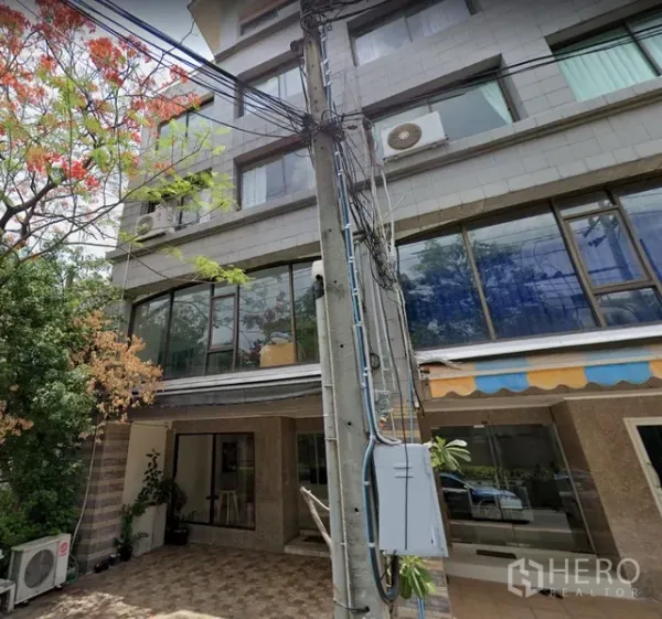 带办公室的家 出租在Watthana, Bangkok - 多层Home Office外立面，大片玻璃窗与瓷砖前院，周围绿树成荫