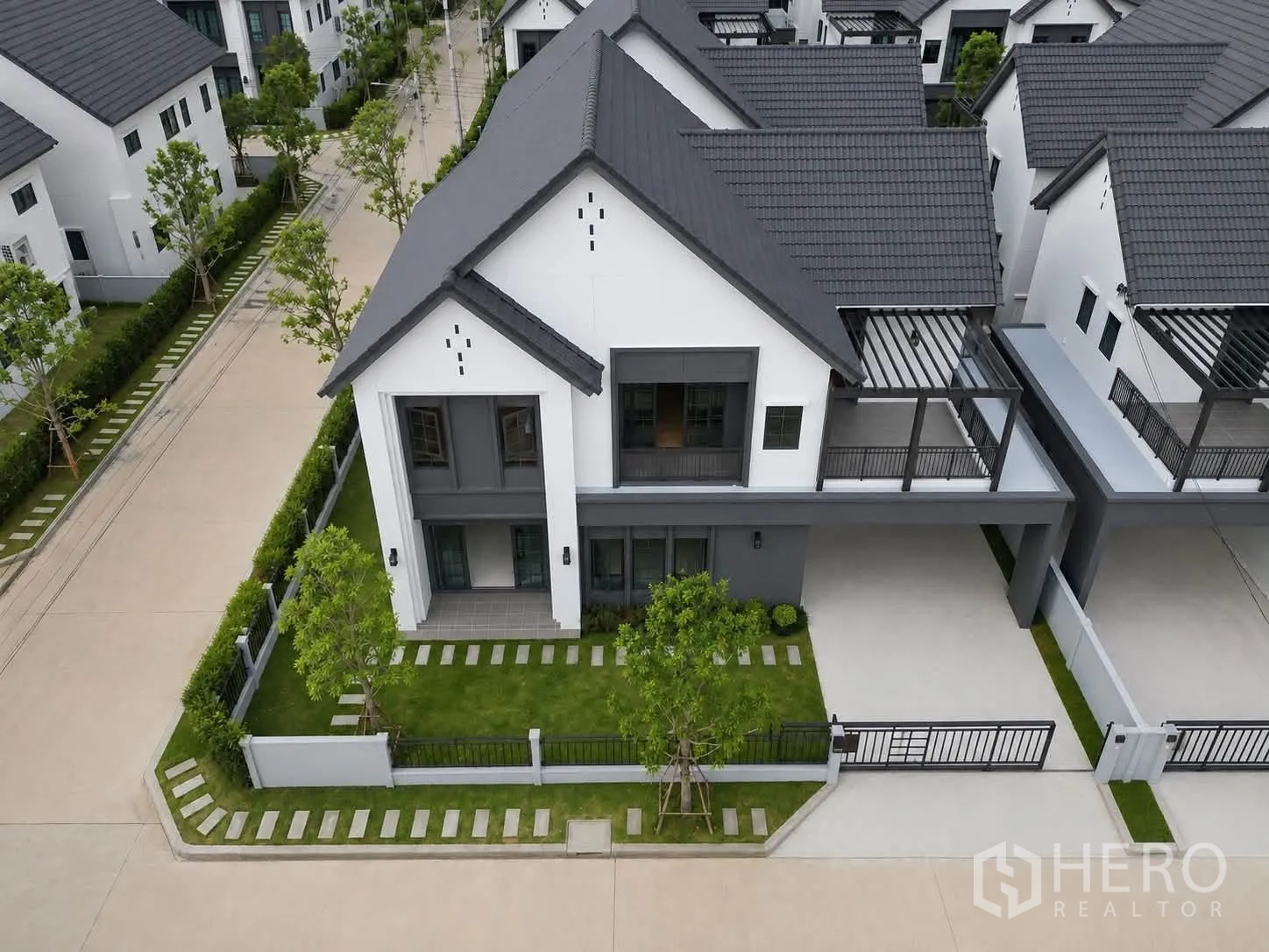 Detached House for rent in Bang Phli, Samut Prakan - Aerial view of a modern two-storey detached house on a corner lot with lawn, fence and covered carport.