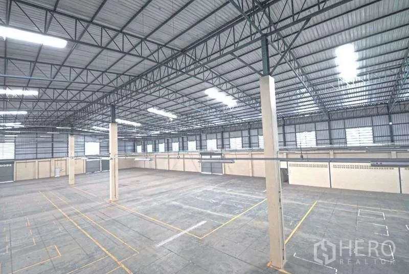 Warehouse for rent in Bang Bo, Samut Prakan - Elevated view across the warehouse showing structural steel roof and marked loading zones.