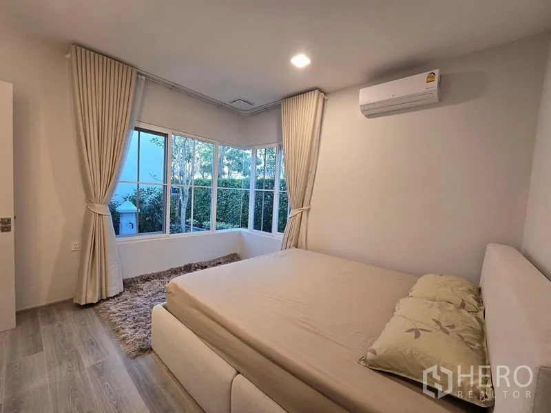 Detached House for rent in Bang Phli, Samut Prakan - Bright bedroom with large corner windows, curtains, air conditioning and garden outlook.