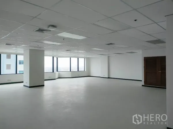 Office Space for rent in Huai Khwang, Bangkok - Spacious corner office area with panoramic windows, white walls, columns, and a clean polished floor.