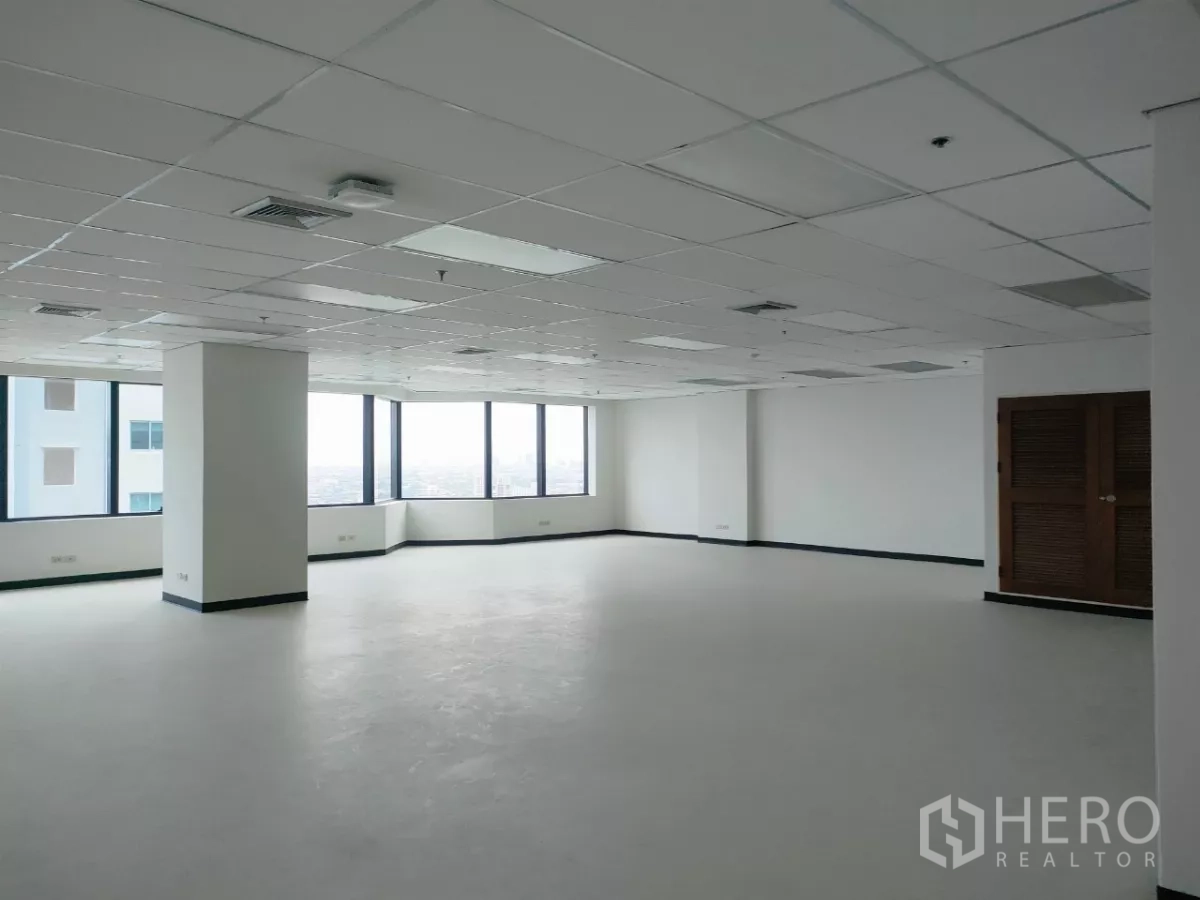 Office Space for rent in Huai Khwang, Bangkok - Spacious corner office area with panoramic windows, white walls, columns, and a clean polished floor.