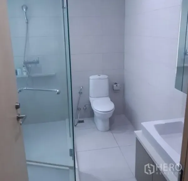 公寓 出租在Khlong Toei, Bangkok - 明亮浴室，玻璃淋浴房与白色瓷砖。
