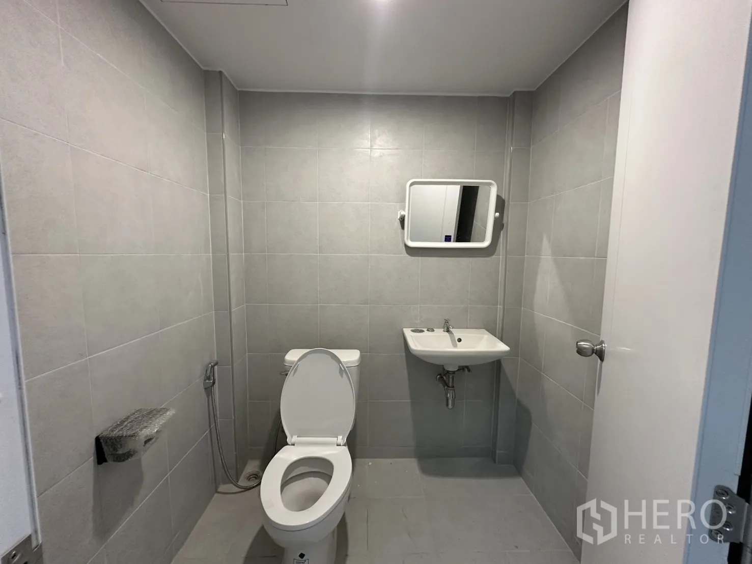 Warehouse for rent in Bang Phli, Samut Prakan - Tiled bathroom with toilet, sink and mirror in neutral tones.