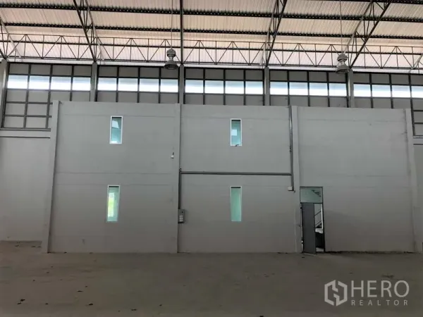 Factory for rent in Lam Luk Ka, Pathum Thani - Two‑storey internal office block inside the warehouse with narrow windows and high clerestory glazing.