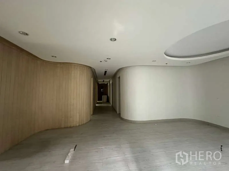 Retail Space for rent in Pathum Wan, Bangkok - Empty retail interior with a curved wood feature wall and ceiling spotlights.