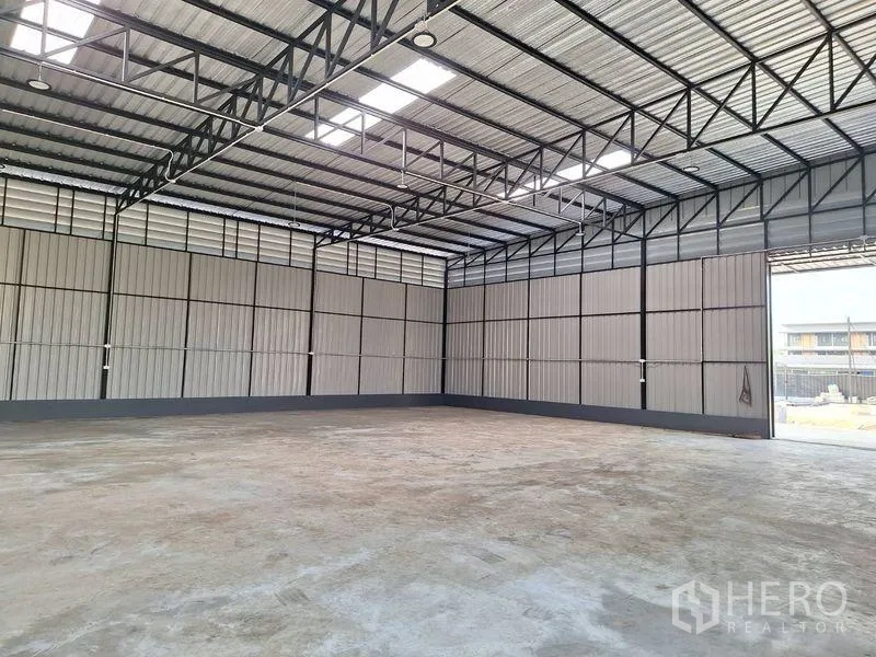 Warehouse for rent in Lat Phrao, Bangkok - Interior view showing open roller door, steel truss ceiling and expansive floor area