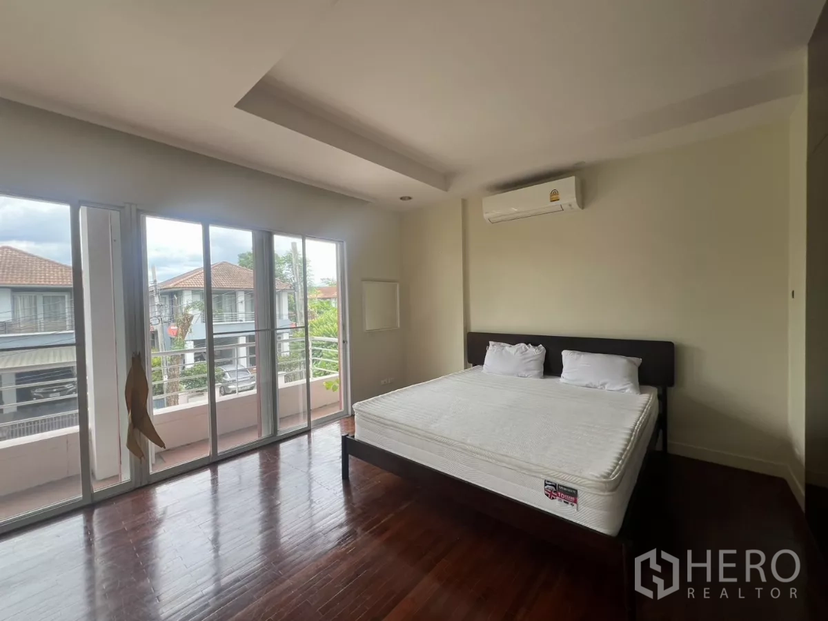 Detached House for rent in Wang Thonglang, Bangkok - Spacious master bedroom with balcony access, wood floors and air conditioner.