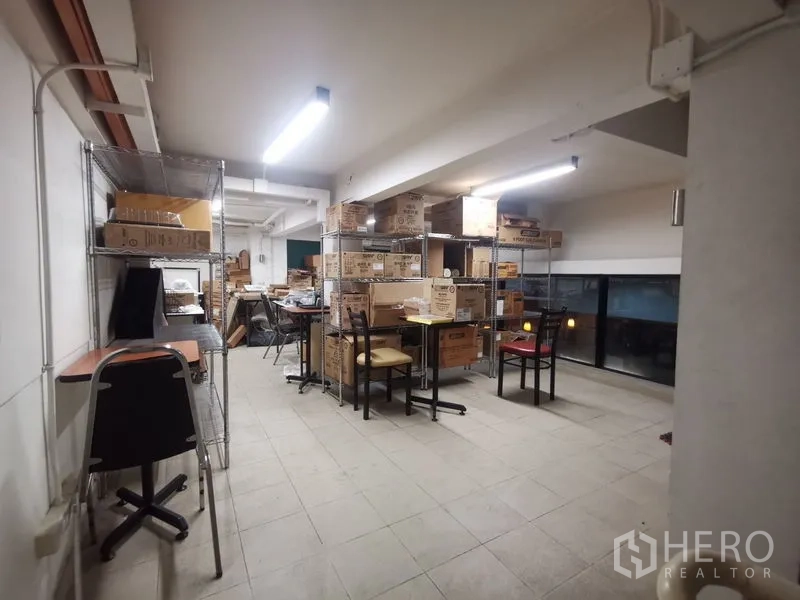 Shophouse for rent in Bangkok - Mezzanine storage room with metal racks, boxes, and work tables.