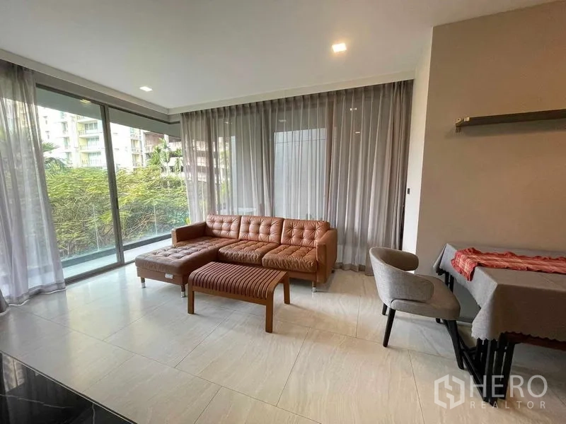 公寓 出租或出售在Watthana, Bangkok - 客厅配L形皮沙发与落地窗。