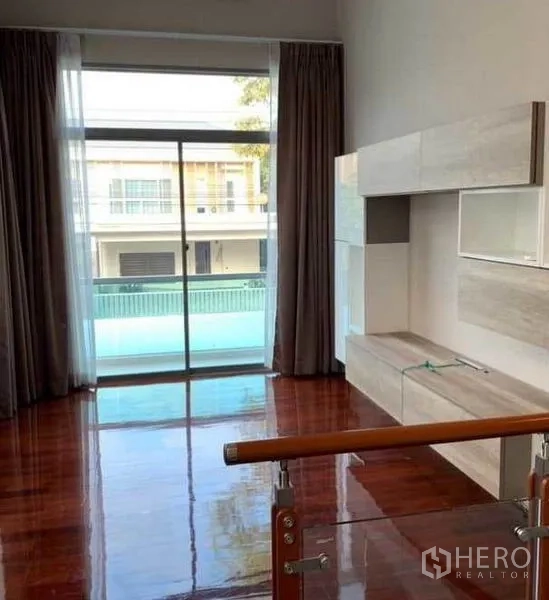 独立式住宅 出售在Mueang Pathum Thani, Pathum Thani - 二楼家庭区，推拉门通往阳台，内置墙柜与木地板。