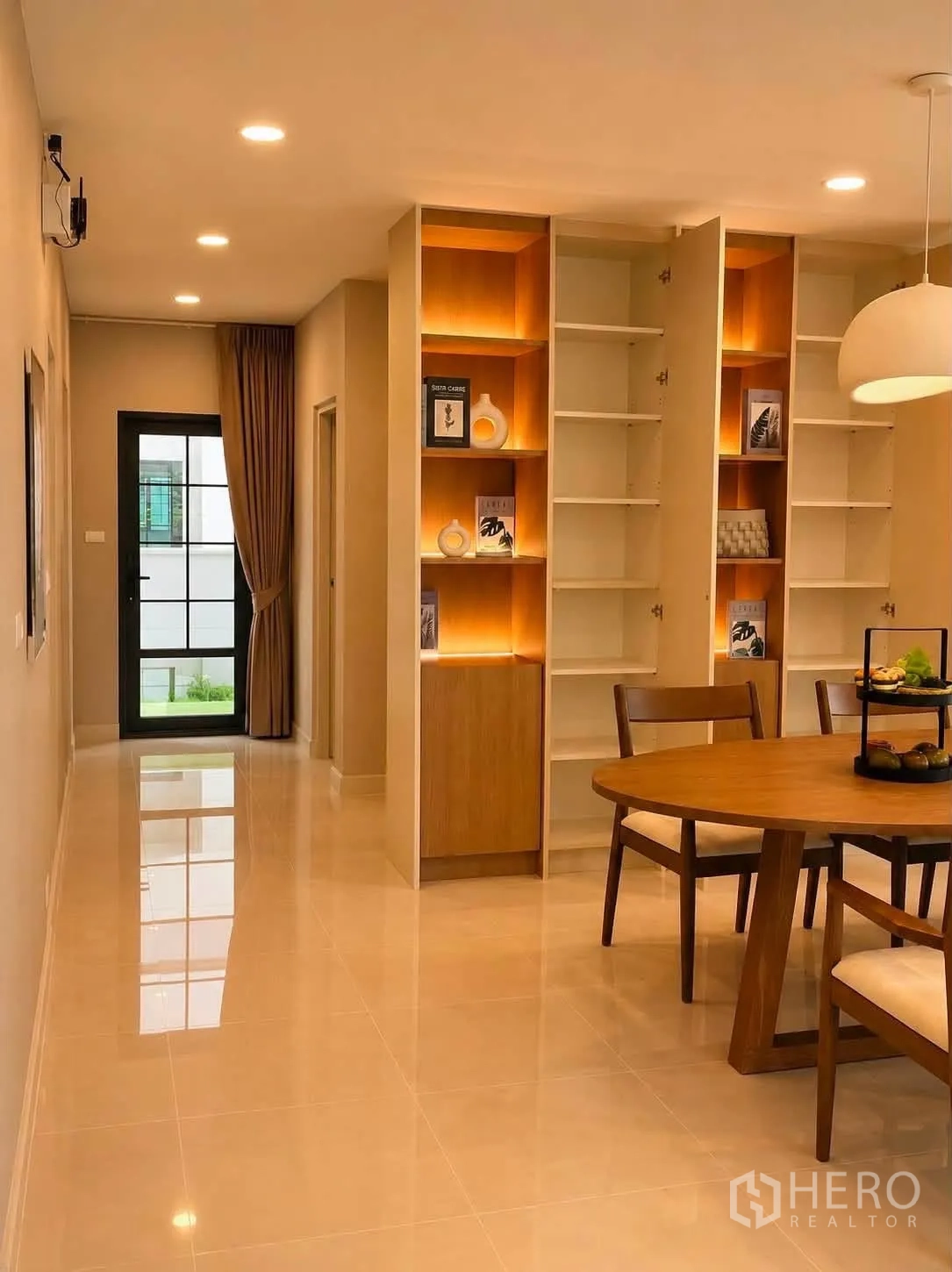 Detached House for rent in Bang Phli, Samut Prakan - Hallway dining area with illuminated built-in shelves and a round wooden table.