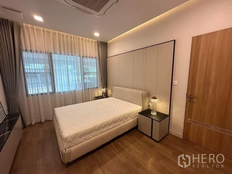 Detached House for rent in Samut Prakan - Ground-floor bedroom with upholstered headboard and wide windows.