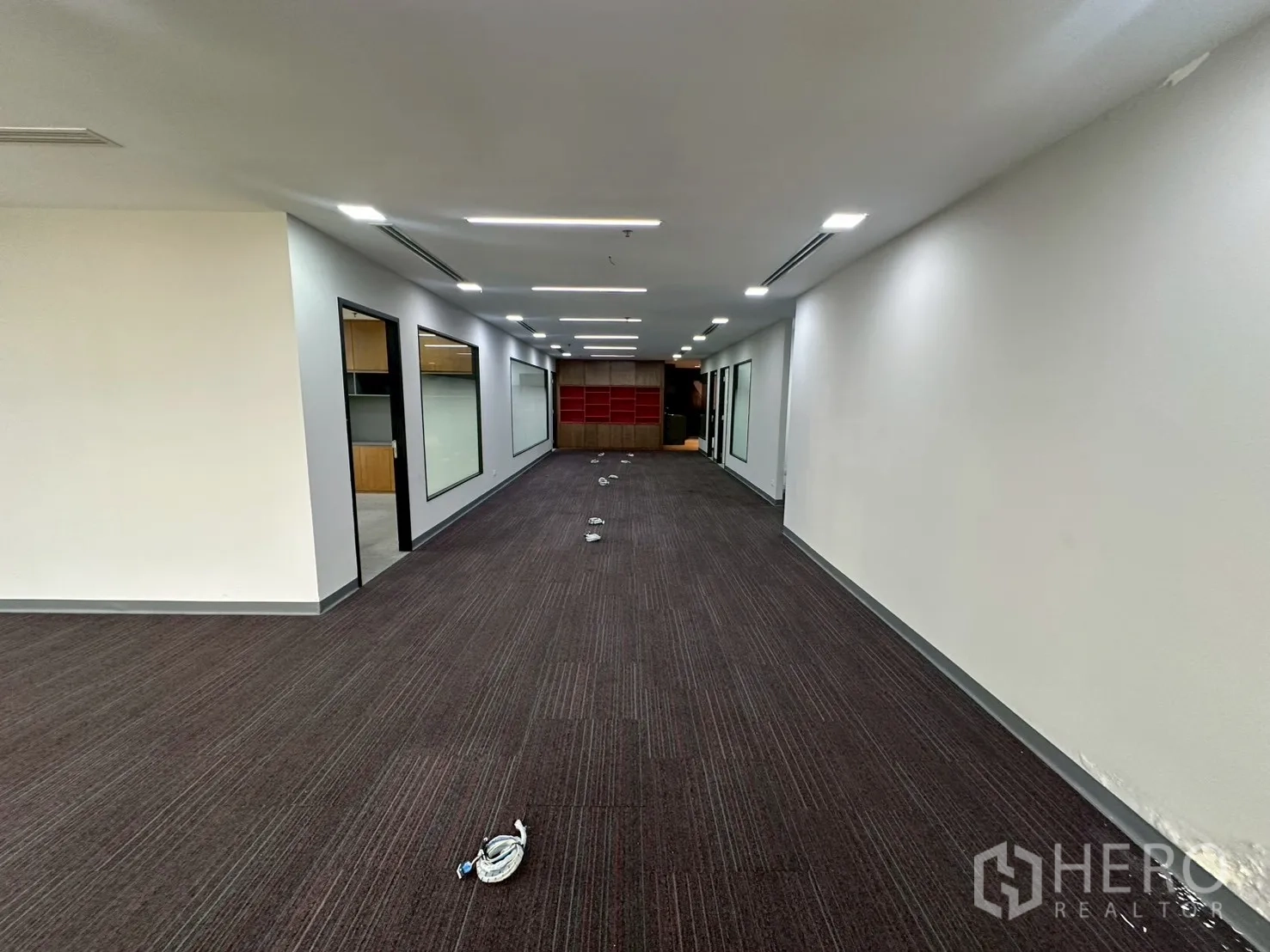Office Space for rent - Deep office layout with glass partitions, built-in shelving and linear ceiling lights.
