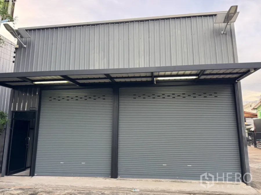 仓库 for rent in Suan Luang, Bangkok - 仓库外观，双卷闸门、雨棚与硬化前院。