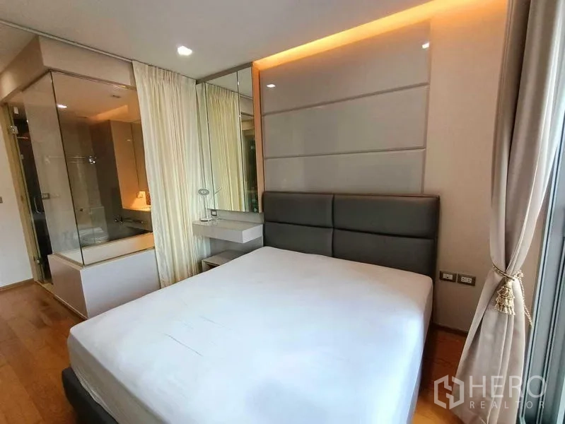 公寓 出租在Ratchathewi, Bangkok - 卧室连接玻璃隔断浴室，设浴缸与镜面装饰，采光柔和。