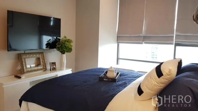公寓 出租在Khlong Toei, Bangkok - 卧室内壁挂电视、大窗与百叶帘及储物柜。