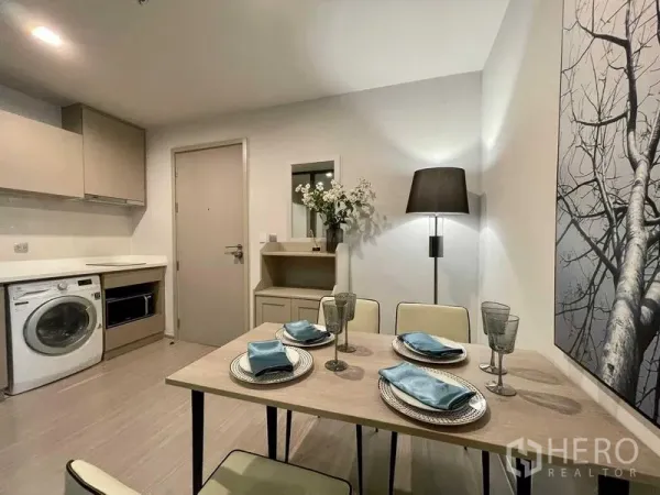 Condominium for rent in Chatuchak, Bangkok - Compact kitchen with washer, built-in cabinets and a four-seat dining table in a modern condo.