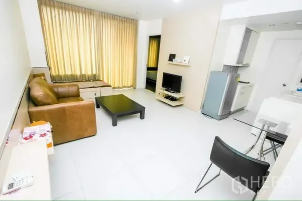Condominium for rent in Ratchathewi, Bangkok - Bright Bangkok condo living room with large curtained window, leather sofa, TV console and small dining area.
