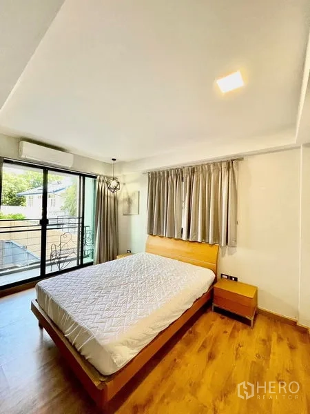 联排别墅 出租在Khlong Toei, Bangkok - 采光良好的卧室，木地板，床，推拉门连通阳台。