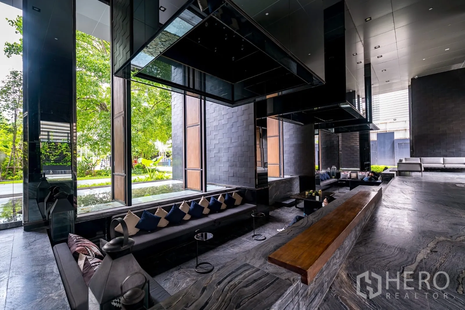 Condominium for rent in Watthana, Bangkok - Shaded semi-outdoor lobby lounge with long bench and greenery.