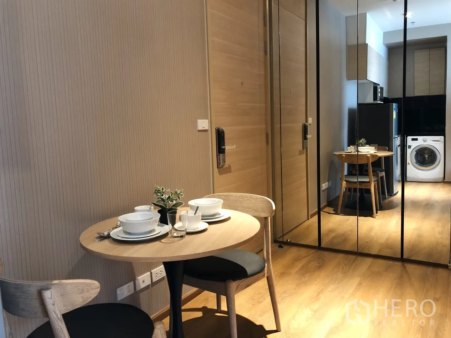 Condominium for rent in Khlong Toei, Bangkok - Dining nook for two with round table and mirrored wall facing the entry and kitchen.