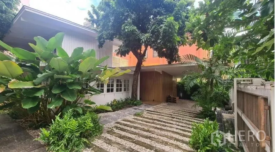 Detached House for rent in Watthana, Bangkok - Front garden and driveway view with mature trees.
