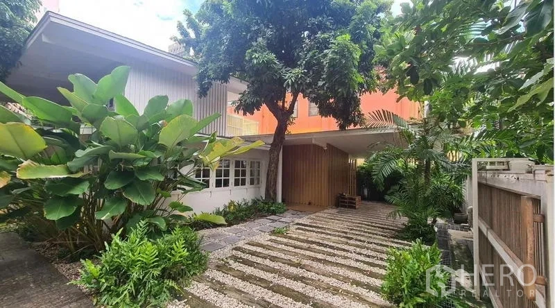 Detached House for rent in Watthana, Bangkok - Front garden and driveway view with mature trees.