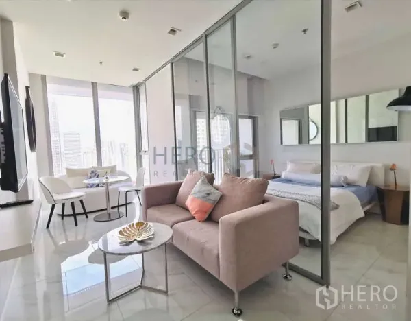 公寓 出租 - HYDE Sukhumvit 11 明亮客厅，沙发与玻璃隔断卧室，远眺城市景观。