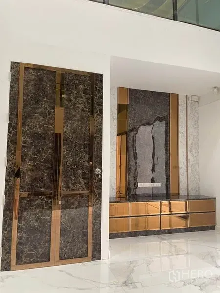 Townhouse for rent or sale in Yan Nawa, Bangkok - Entry area with marble-look wall, bronze accents, built-in console, and glossy white flooring.