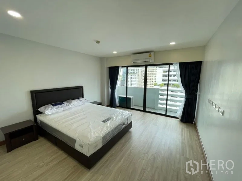 公寓 出租或出售在Watthana, Bangkok - 宽敞卧室，铺木地板，配大床与落地移门，通往可观赏曼谷天际线的阳台。